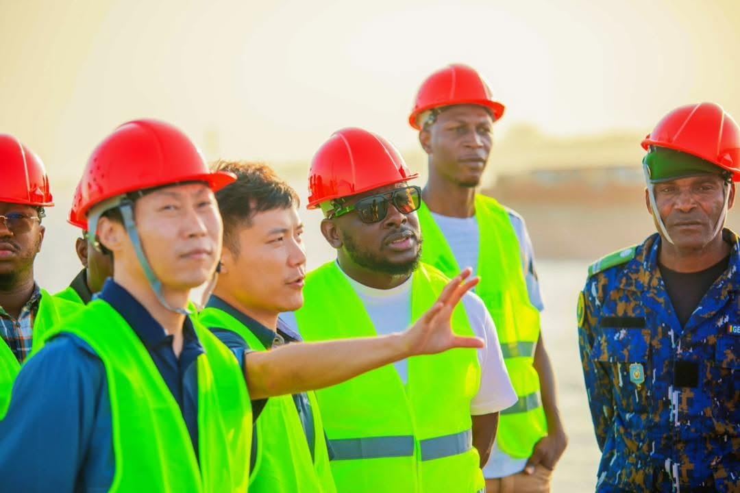 Visite de chantier : Bakary DIABY, en casque rouge et gilet haute visibilité, en discussion technique avec ses partenaires et ingénieurs, tous en équipements de protection